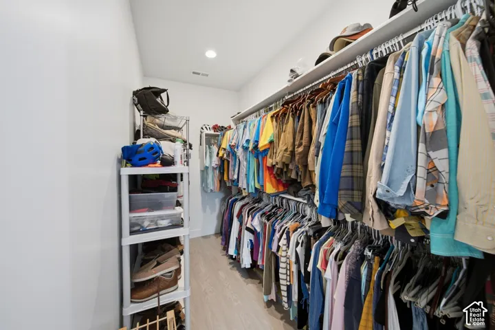 Walk-in closet featuring light wood-finish flooring, recessed lighting, and white walls