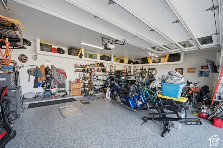 Garage featuring epoxy-coated flooring, built-in overhead storage shelves, and wall-mounted shelving