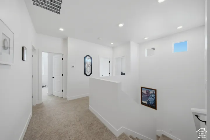 Recessed ceiling lighting, white interior doors, black door hardware, carpet flooring, and upper wall windows