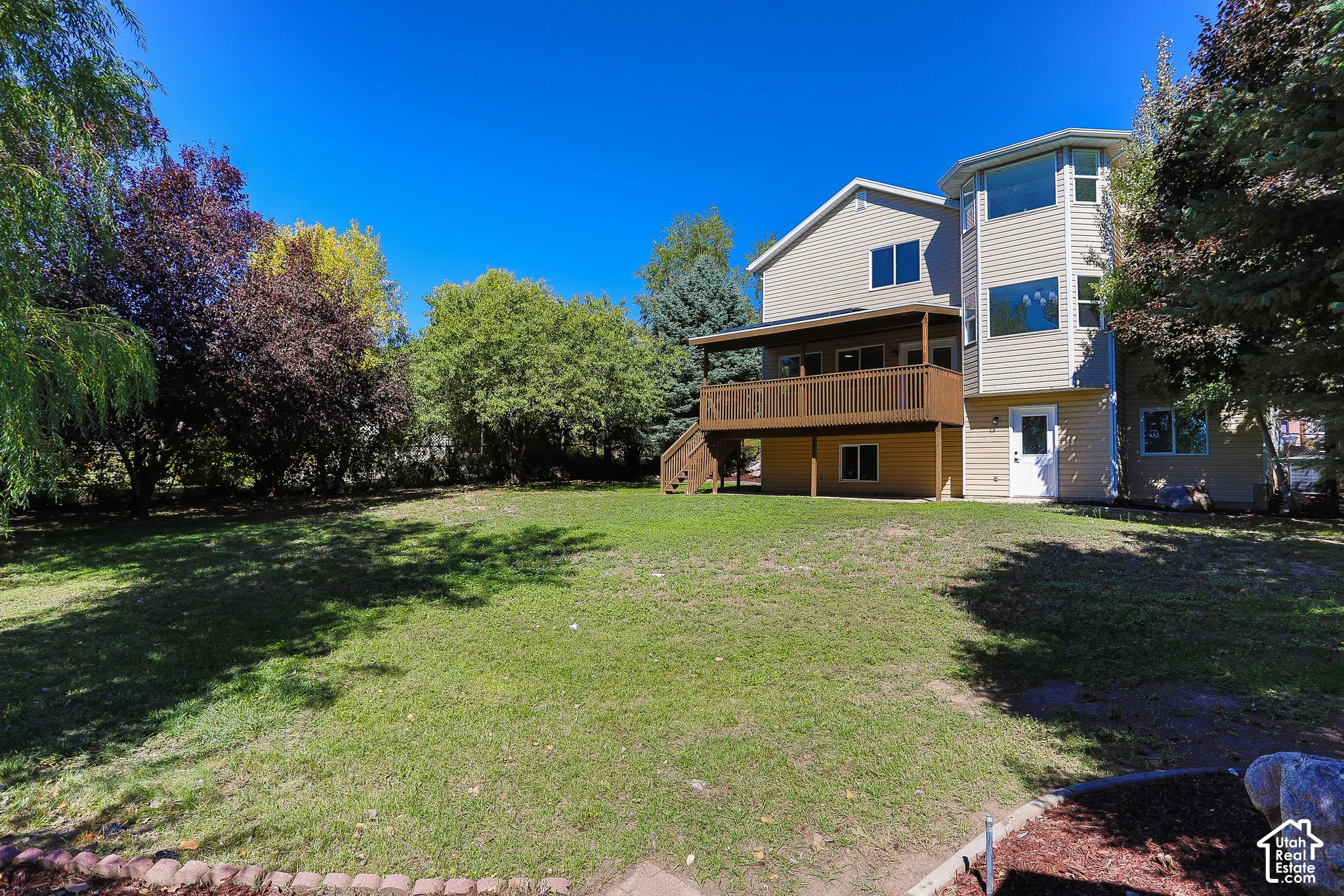 Expansive lawn with mature trees and a multi-level deck