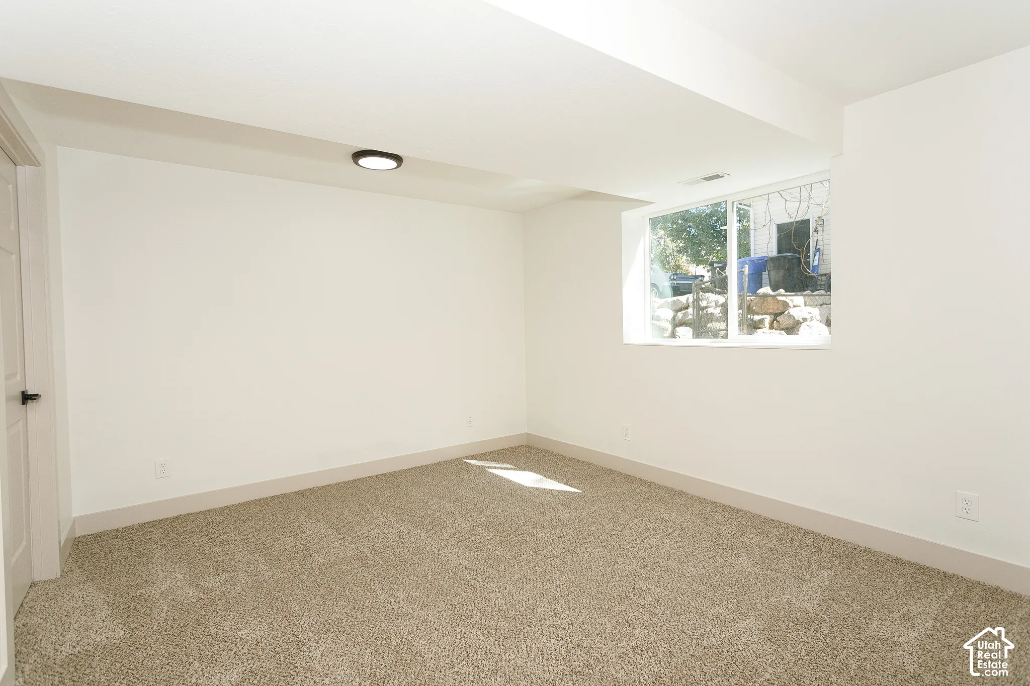 Carpeted room with white painted walls, a flush-mount ceiling light, and a single window