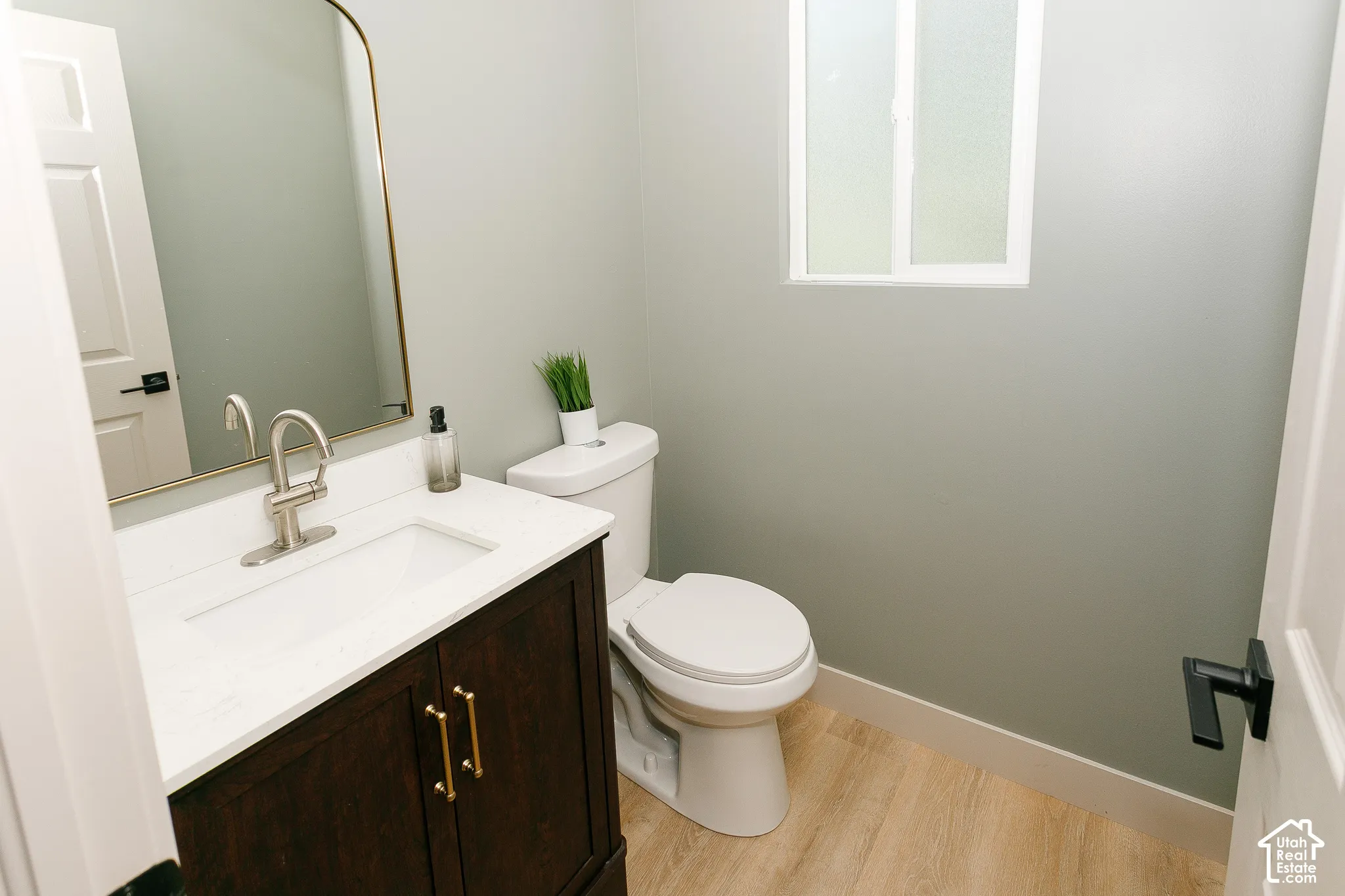 Dark wood-finish vanity with gold-tone hardware, white countertop, and integrated sink