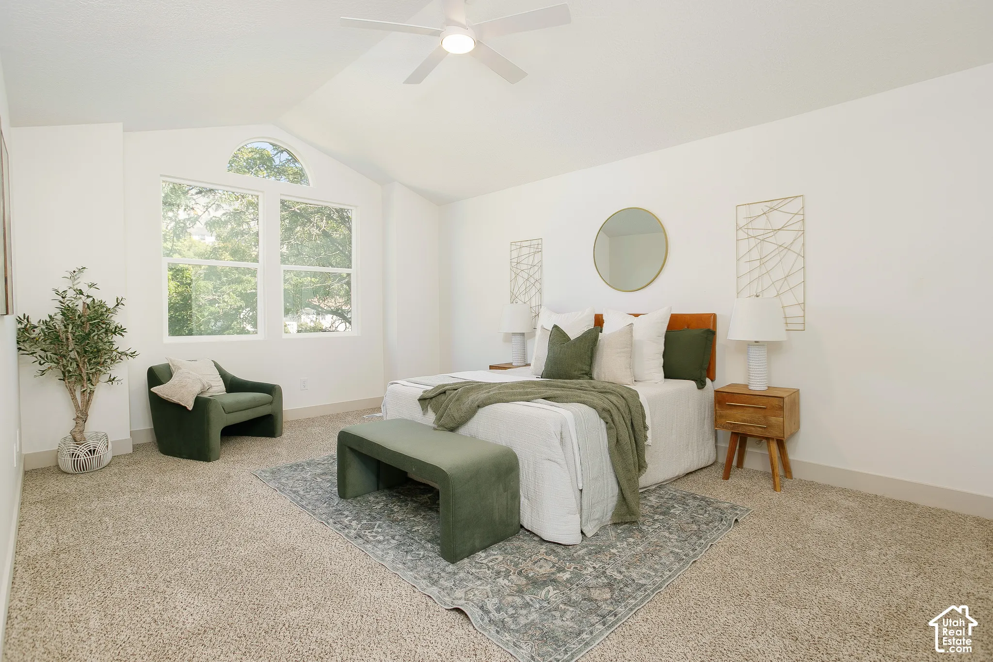 Vaulted ceiling with a ceiling fan, light-colored carpeting, and a large window with an arched transom