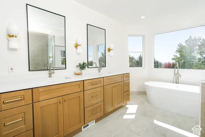 Dual vanity with light wood-finish cabinetry, white countertops, and undermount sinks