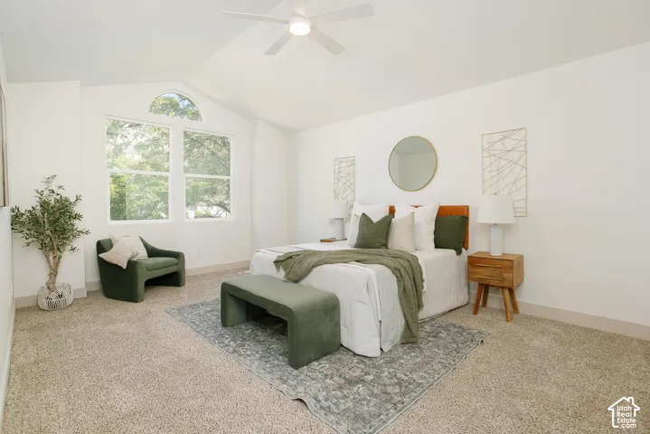 Vaulted ceiling with a ceiling fan, light-colored carpeting, and a large window with an arched transom