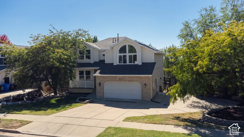 Two-story exterior with a stucco and stone facade, a prominent arched window, a two-car garage, and an inviting front porch
