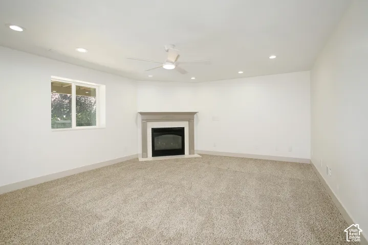 Carpeted room with a corner fireplace, recessed lighting, ceiling fan, and a double-hung window