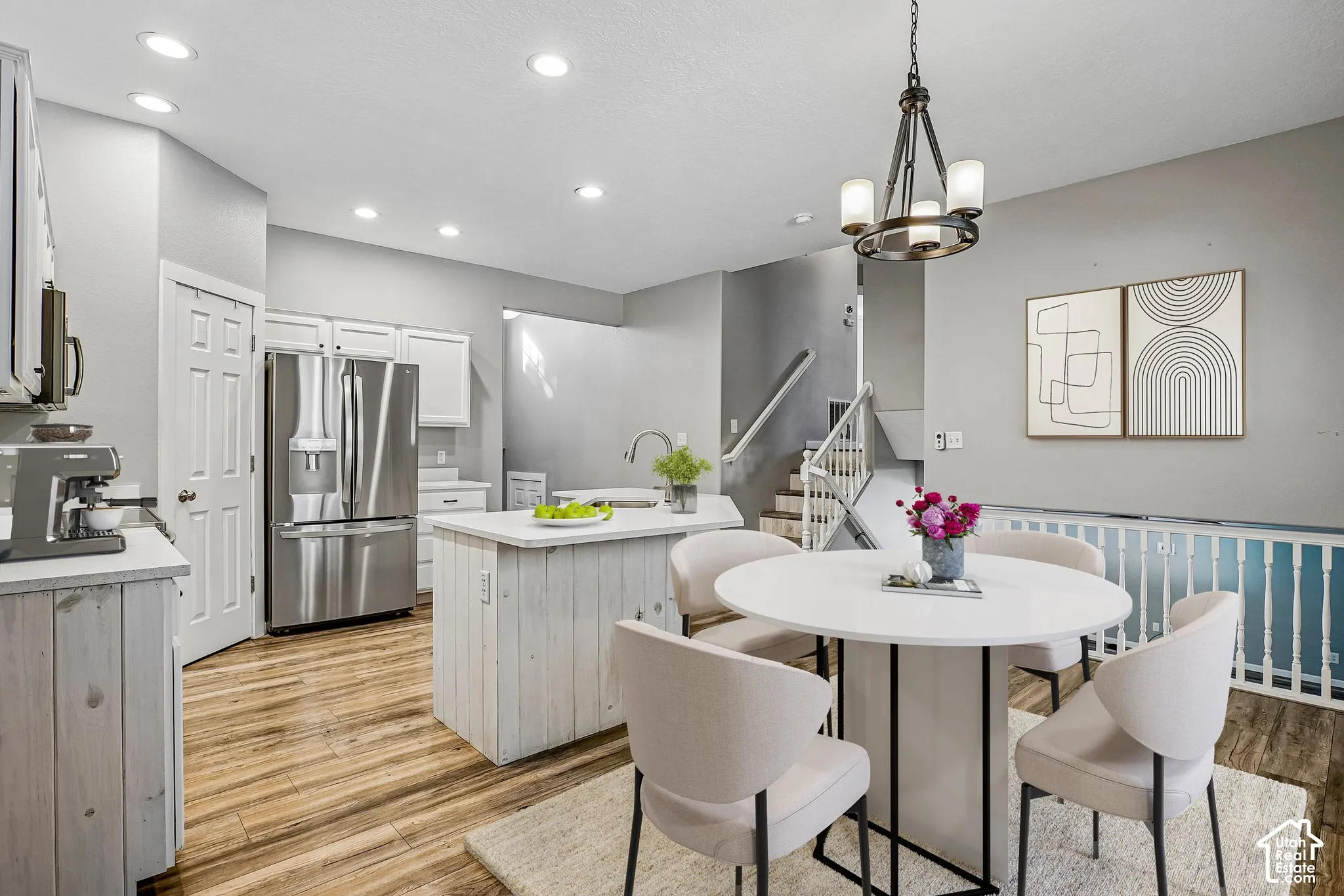 Integrated kitchen and dining area featuring wood-finish flooring, white cabinetry, and stainless steel appliances