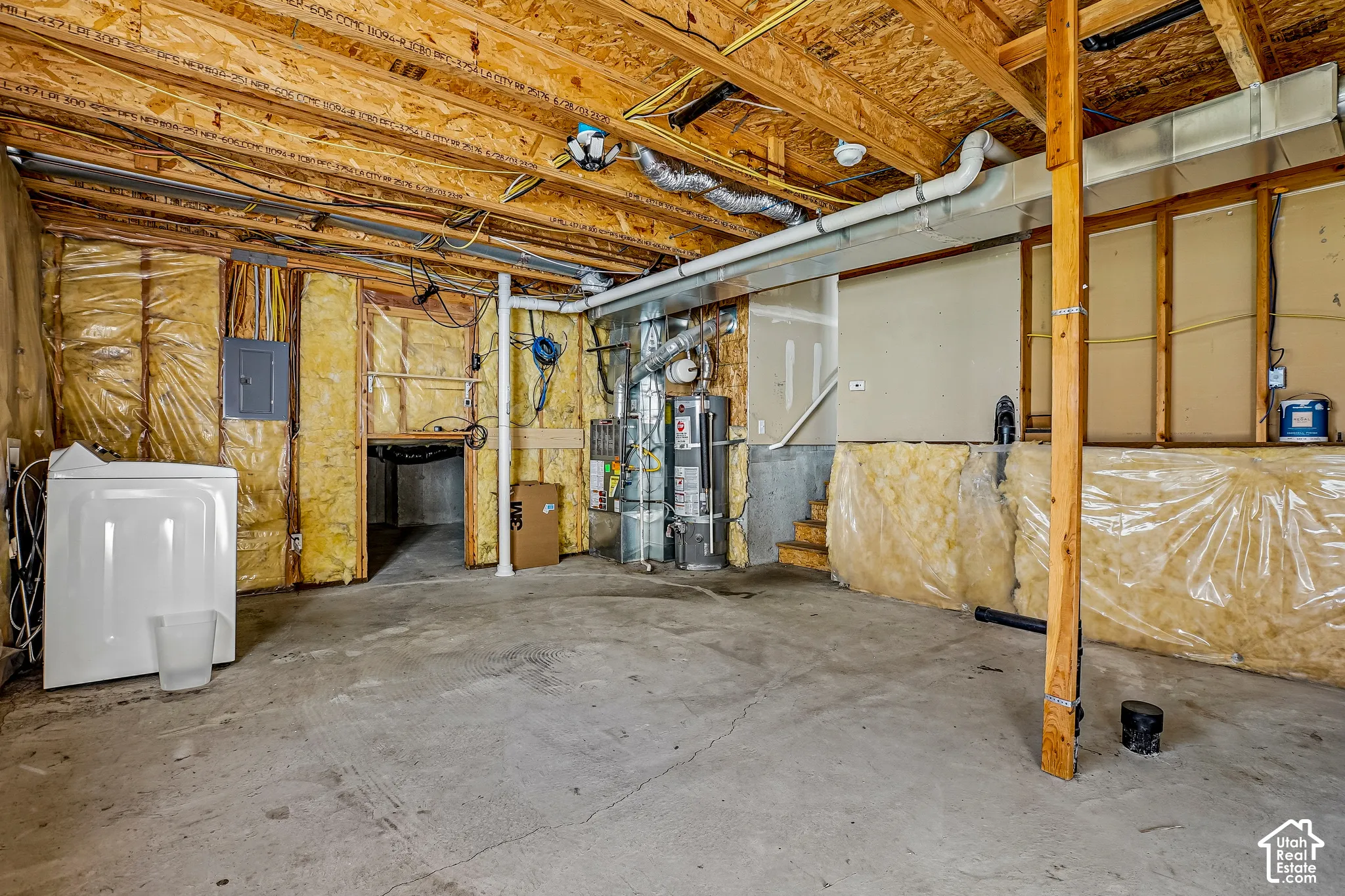 Unfinished basement with exposed ceiling joists, concrete flooring, and insulated walls