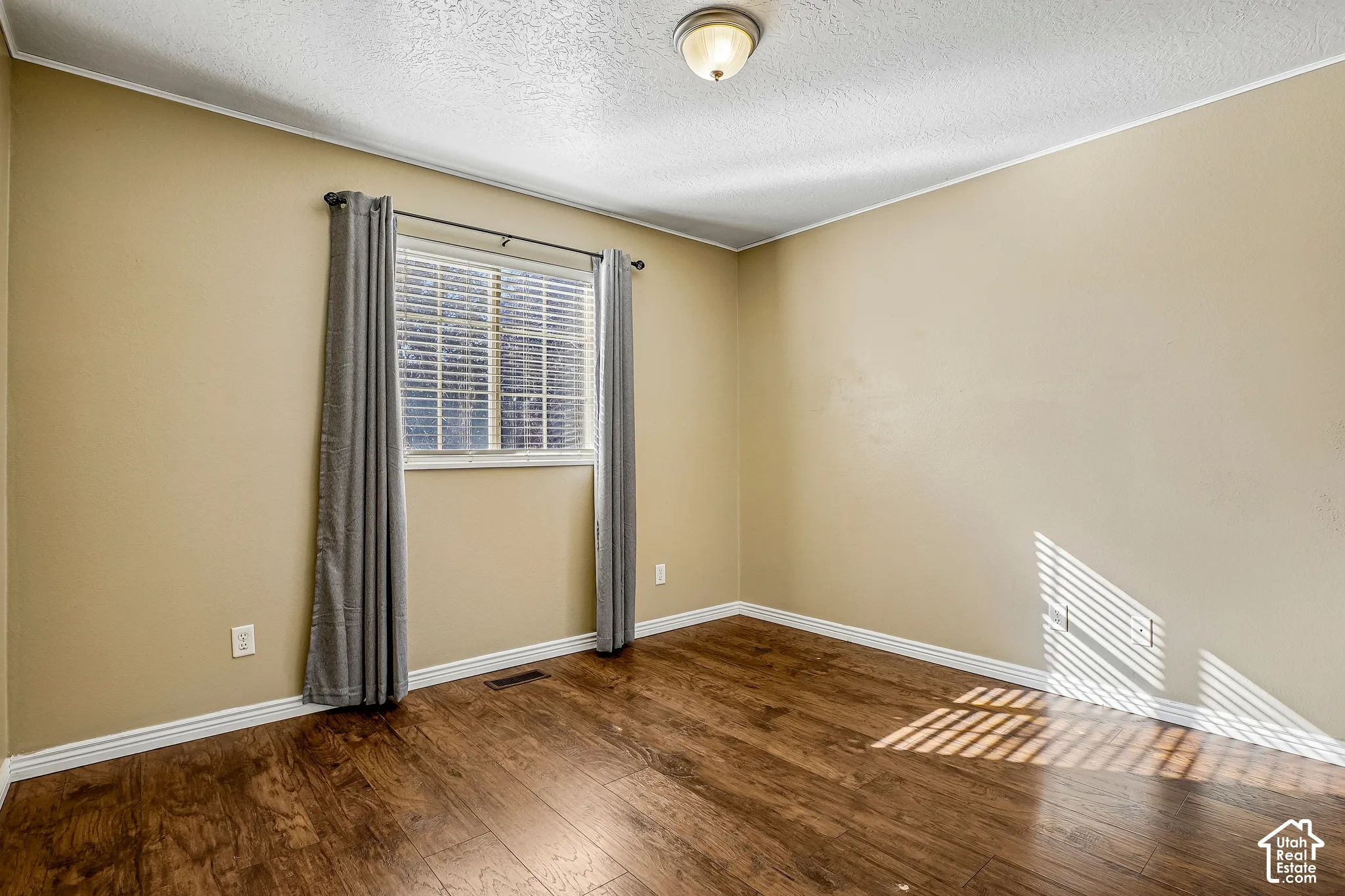 Window with blinds, wood-finish flooring, and a flush mount ceiling light