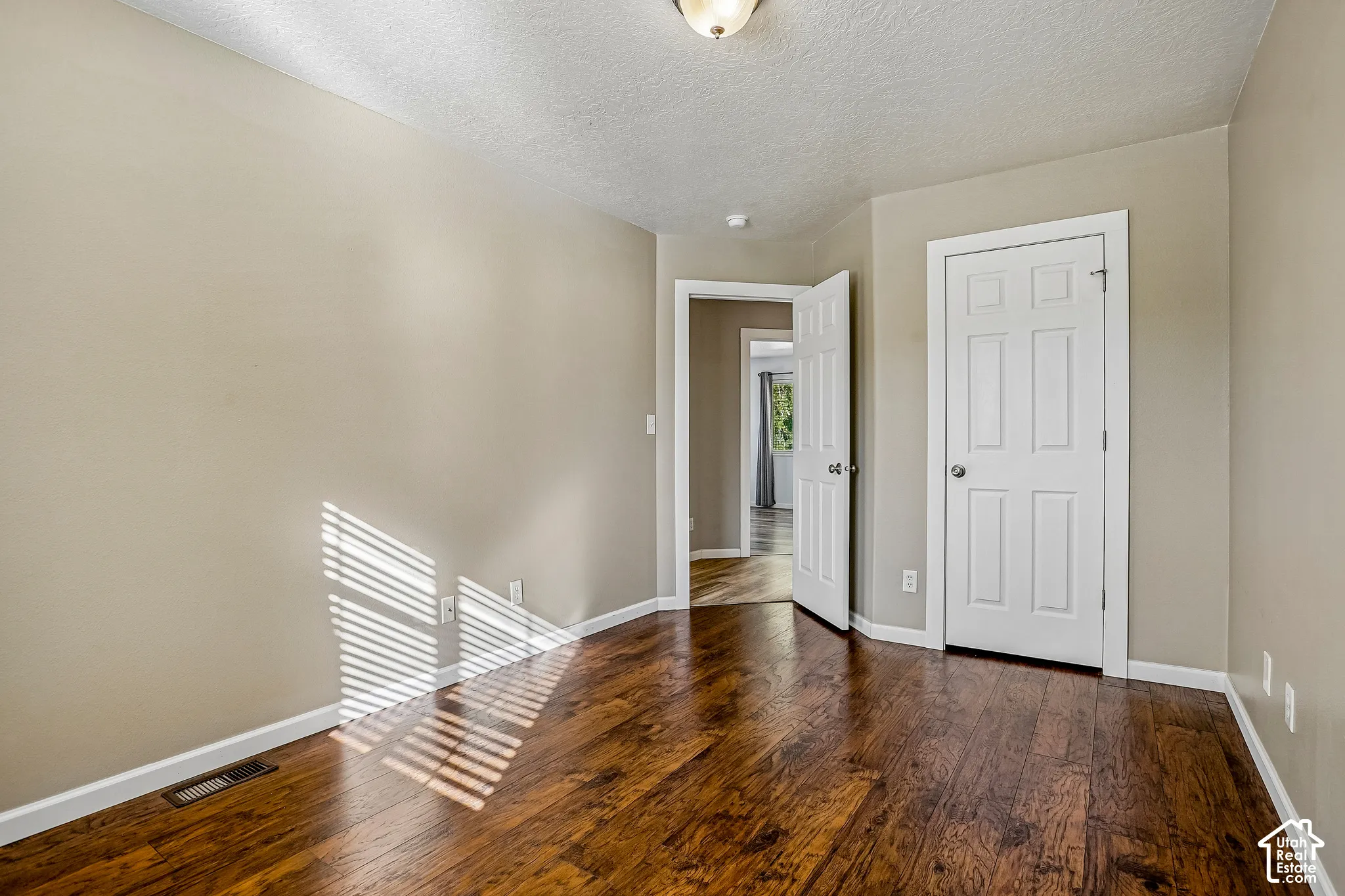 Wood-finish flooring with a semi-gloss finish, neutral wall paint, white trim, and a semi-flush mount ceiling light