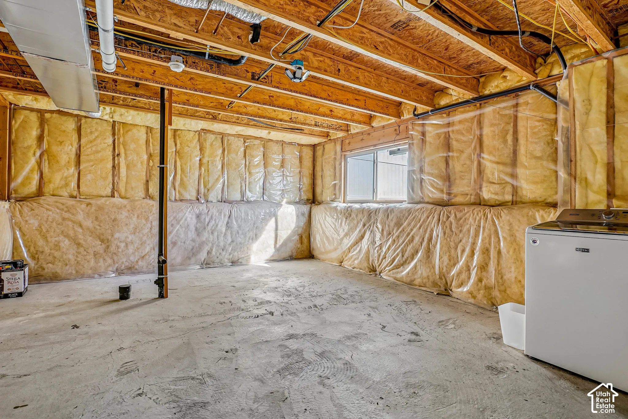 Unfinished basement featuring exposed wood joists, concrete flooring, and insulated walls