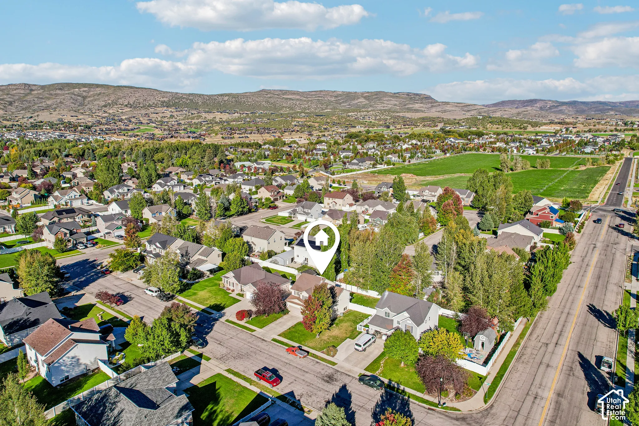 Residential community with mature trees, green spaces, and mountain backdrop