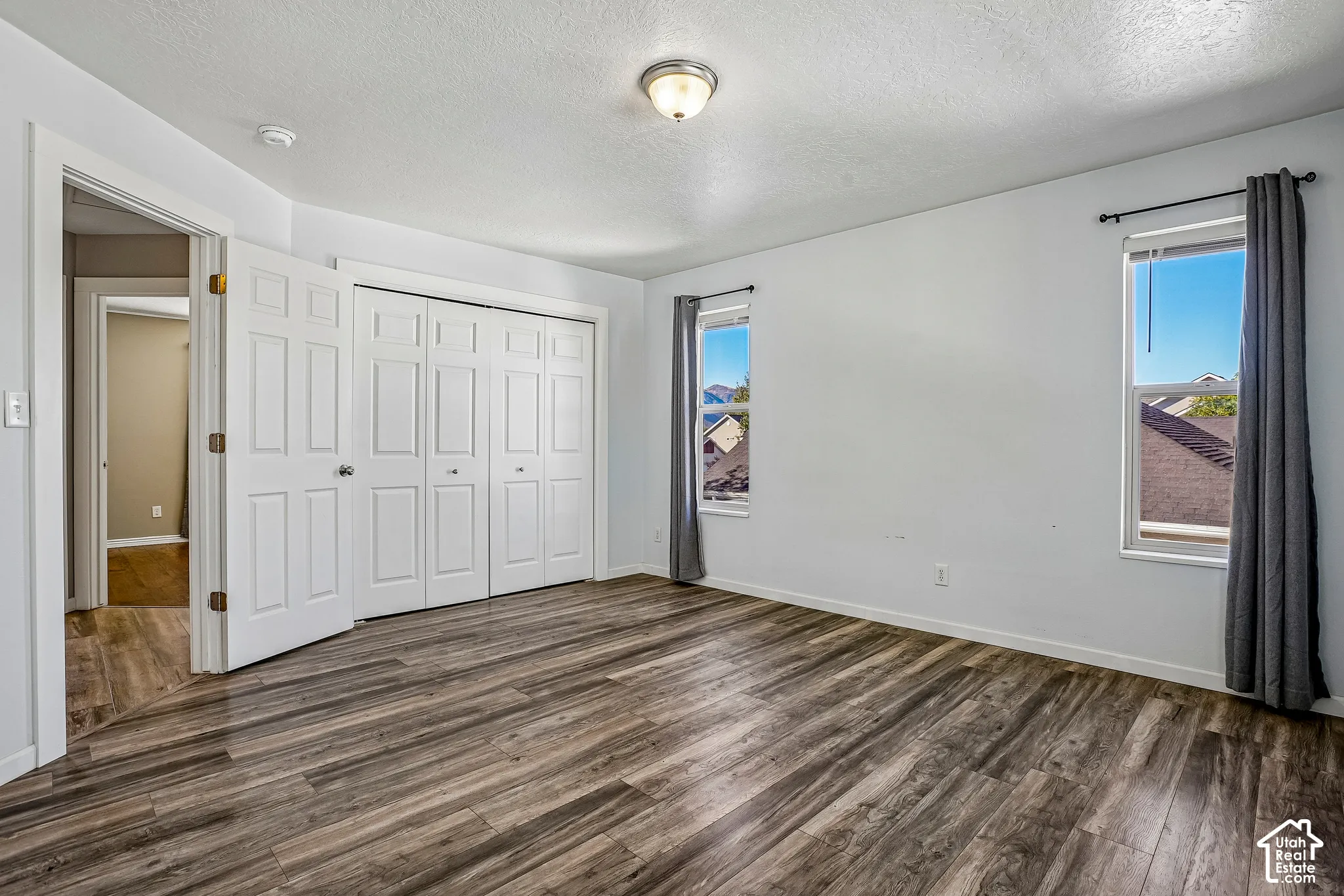 Wood-finish flooring, two windows with blinds, recessed lighting, and white bi-fold closet doors