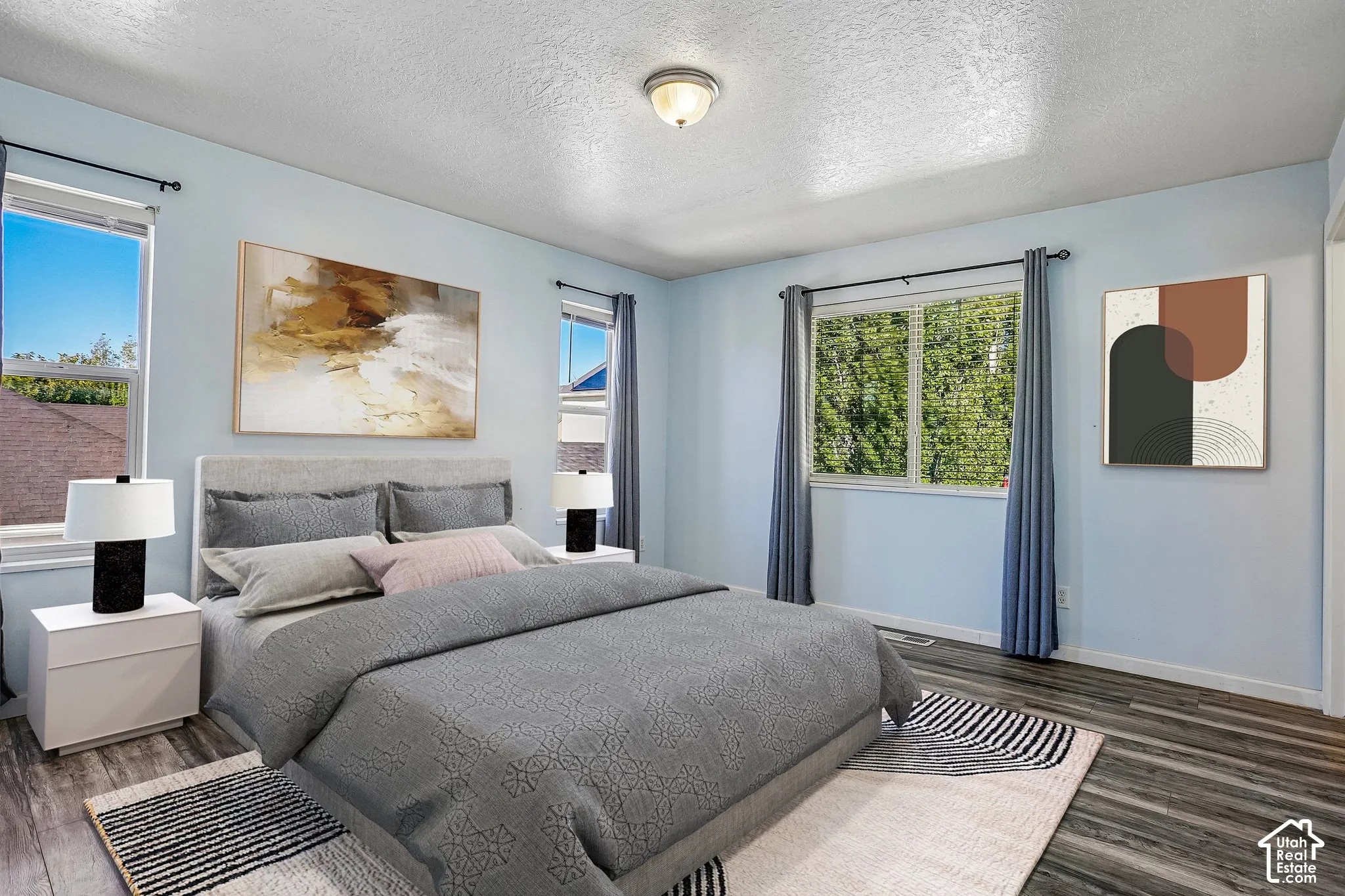 Wood-finish flooring with light blue walls, multiple windows, and a ceiling-mounted light fixture