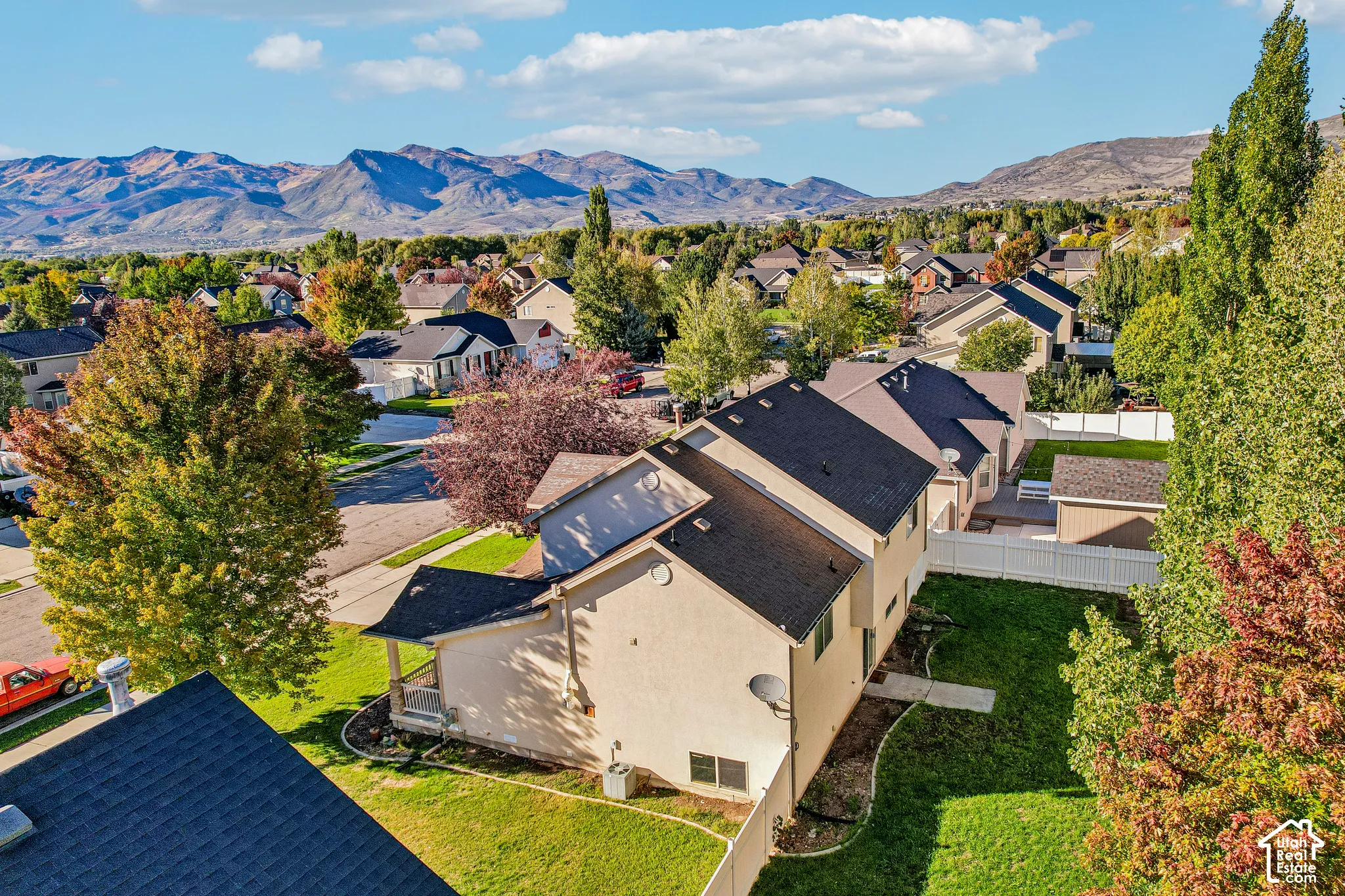 Residential neighborhood with mature trees, mountain backdrop, and clear skies