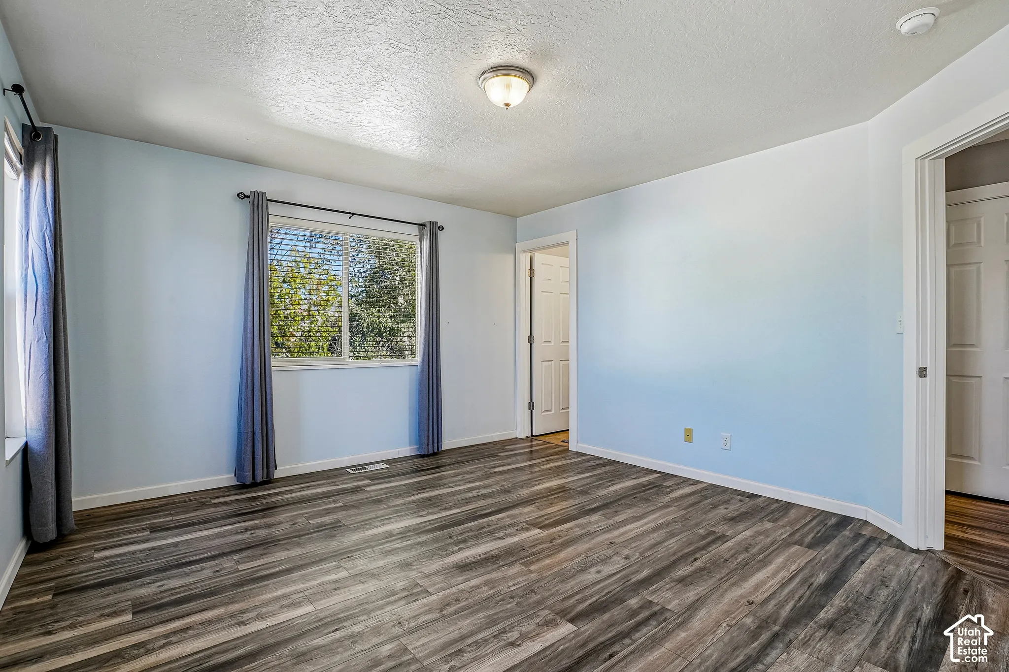 Wood-finish flooring throughout, light blue walls, and multiple white paneled doors