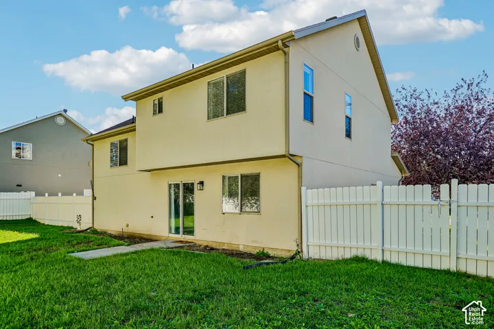 Two-story exterior with a sliding glass door, multiple windows, and a white privacy fence