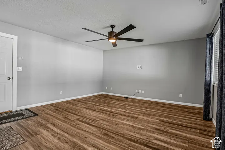 Wood-finish flooring, ceiling fan with light fixture, window with blinds, and white trim