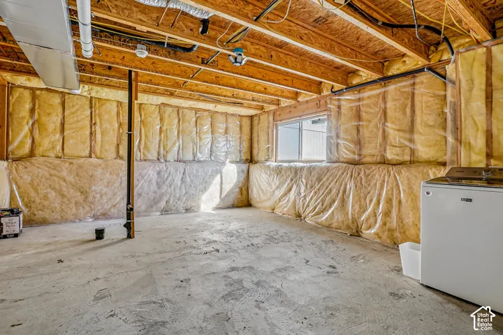 Unfinished basement featuring exposed wood joists, concrete flooring, and insulated walls
