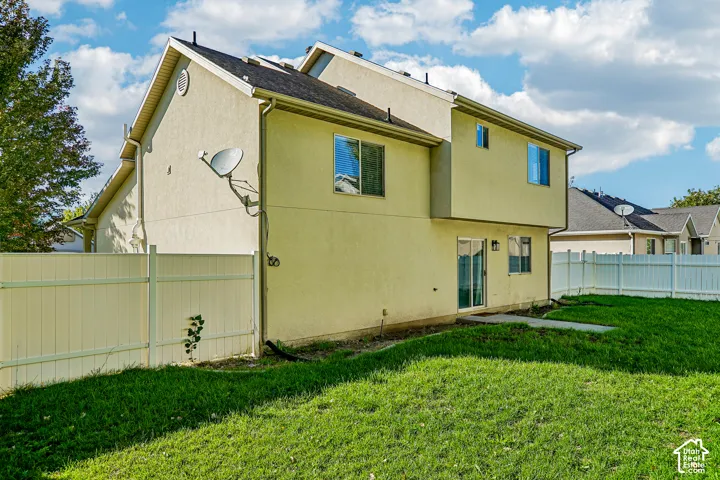 Exterior featuring stucco siding, multiple windows, a sliding glass door, and a white privacy fence