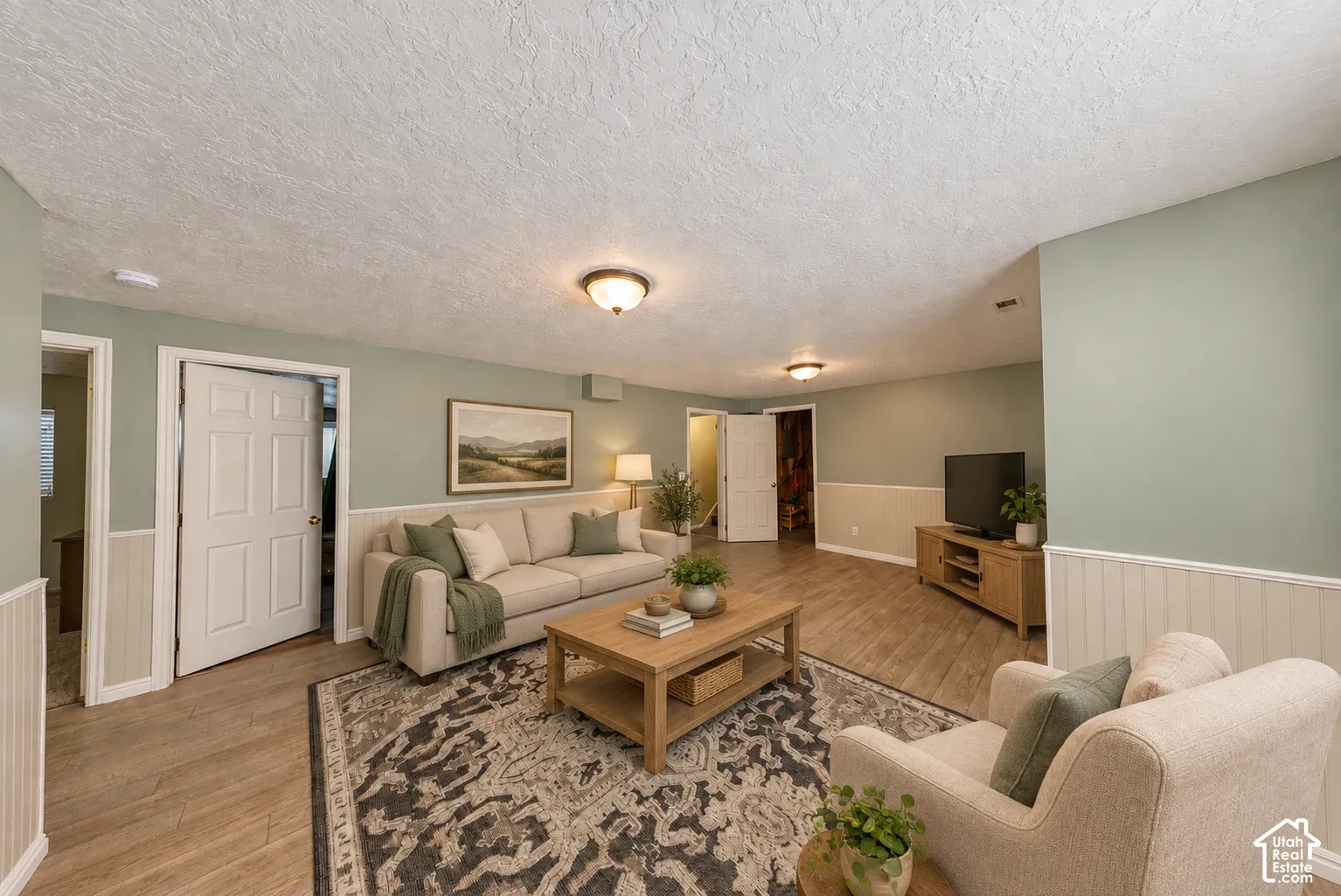 Wood-finish flooring, wainscoting, flush-mount lighting, and neutral wall tones