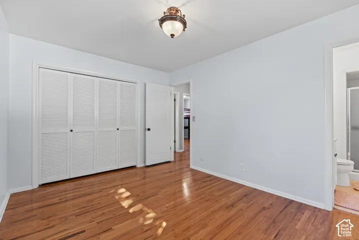 Hardwood flooring, louvered bi-fold closet doors, white trim, and a ceiling-mounted light fixture
