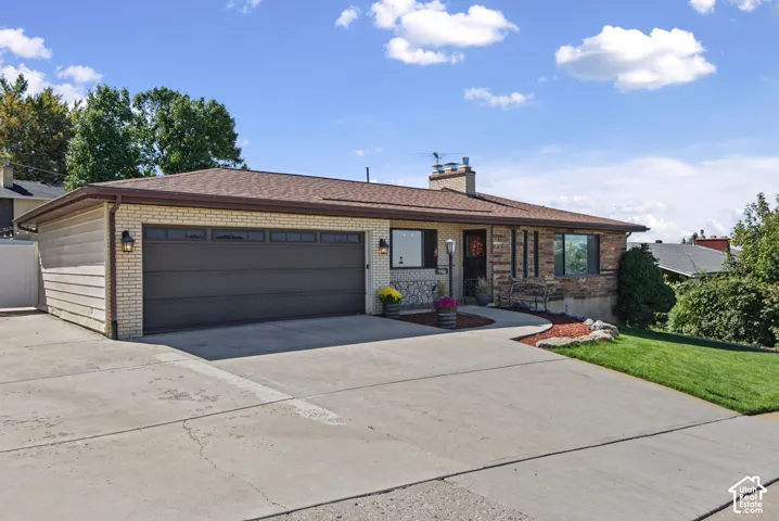 Ranch-style exterior featuring brick and horizontal siding, an attached two-car garage with transom windows, and a concrete driveway