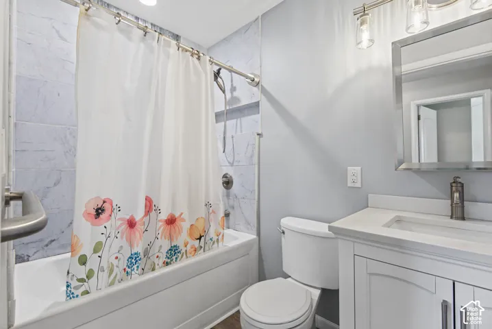 Bathroom featuring a tub/shower combination with tiled surround, a toilet, a vanity with an integrated sink, and an overhead light fixture