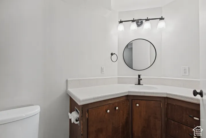 White porcelain sink with matte black faucet, set into a corner vanity with wood-finish cabinetry