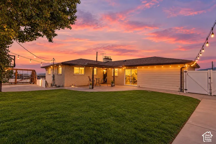 Brick exterior, attached garage, covered patio, white fencing, and concrete patio