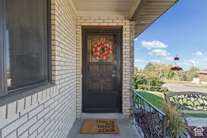 Light-toned brick exterior with a dark-framed entry door, and a wrought iron railing