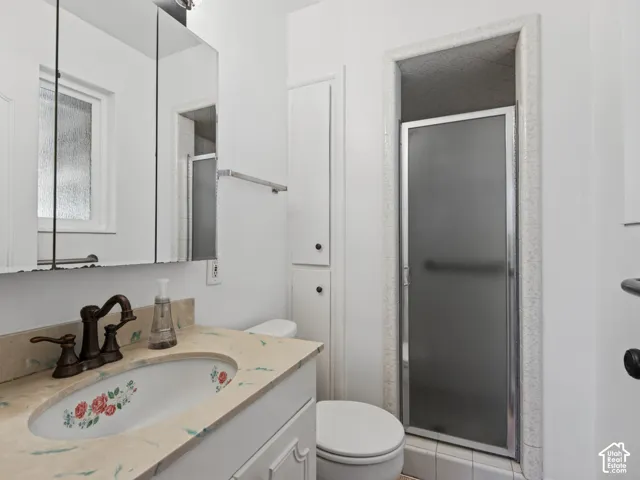 Vanity with an integrated sink and bronze-finish faucet, framed medicine cabinet, built-in storage cabinetry, and a shower enclosure