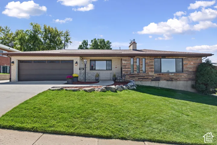 Brick exterior with stone facade accents, attached two-car garage, concrete driveway, and front lawn