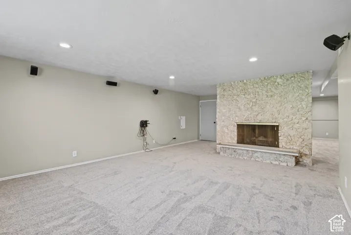 Stone-clad fireplace with a hearth, recessed lighting, and neutral carpeting