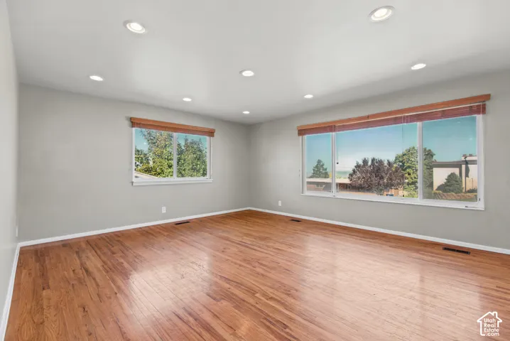 Recessed lighting, wood-finish flooring, and multiple windows with wood window treatments