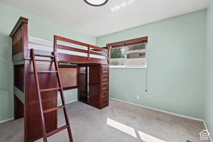 Carpeted room featuring a window with a wood-finish frame, a ceiling-mounted light fixture, and light-toned walls