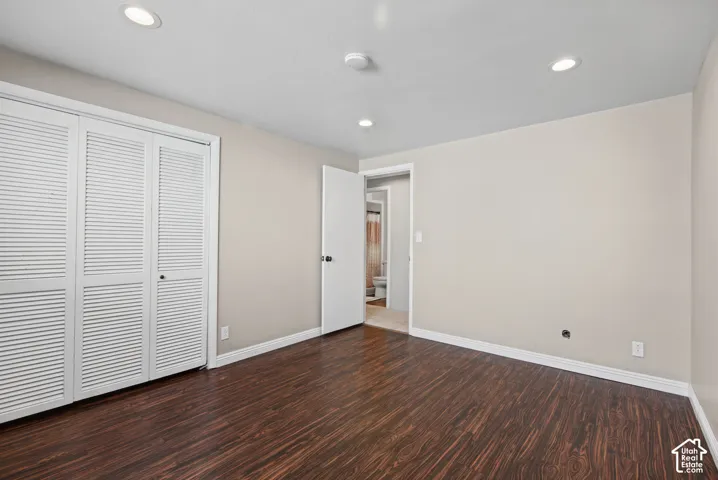 Wood-finish flooring with white baseboards, recessed lighting, and white louvered closet doors