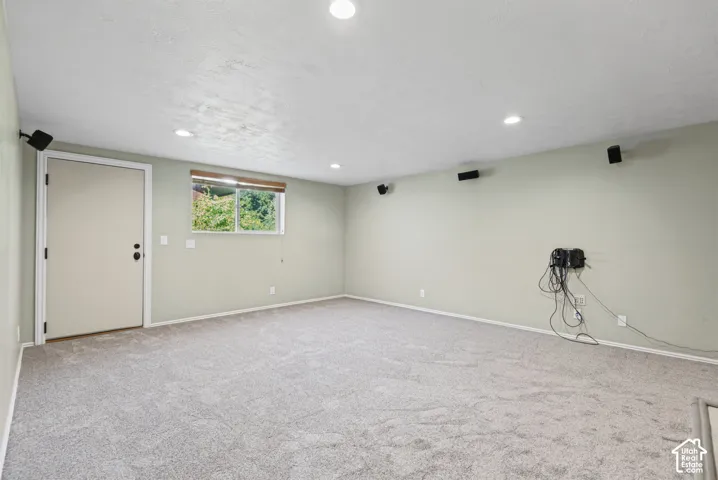 Recessed lighting, light gray carpeting, neutral wall color, and a window with exterior visibility