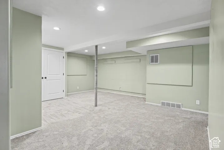 Recessed lighting illuminates the carpeted room featuring a white paneled door with dark hardware