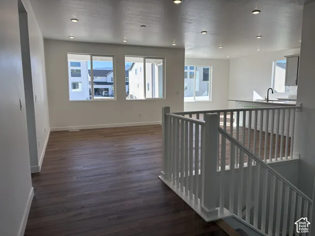 Open-concept living area with wood-finish flooring, white walls, recessed lighting, and lot of natural light