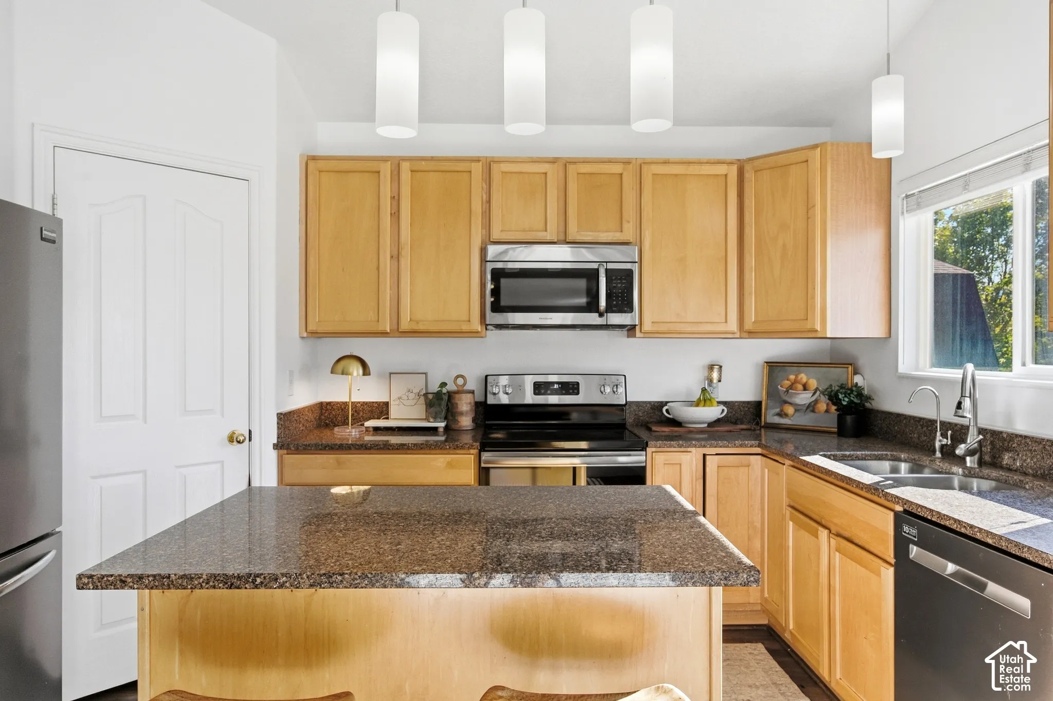 Kitchen featuring granite countertops, wood cabinetry, stainless steel appliances, and pendant lighting
