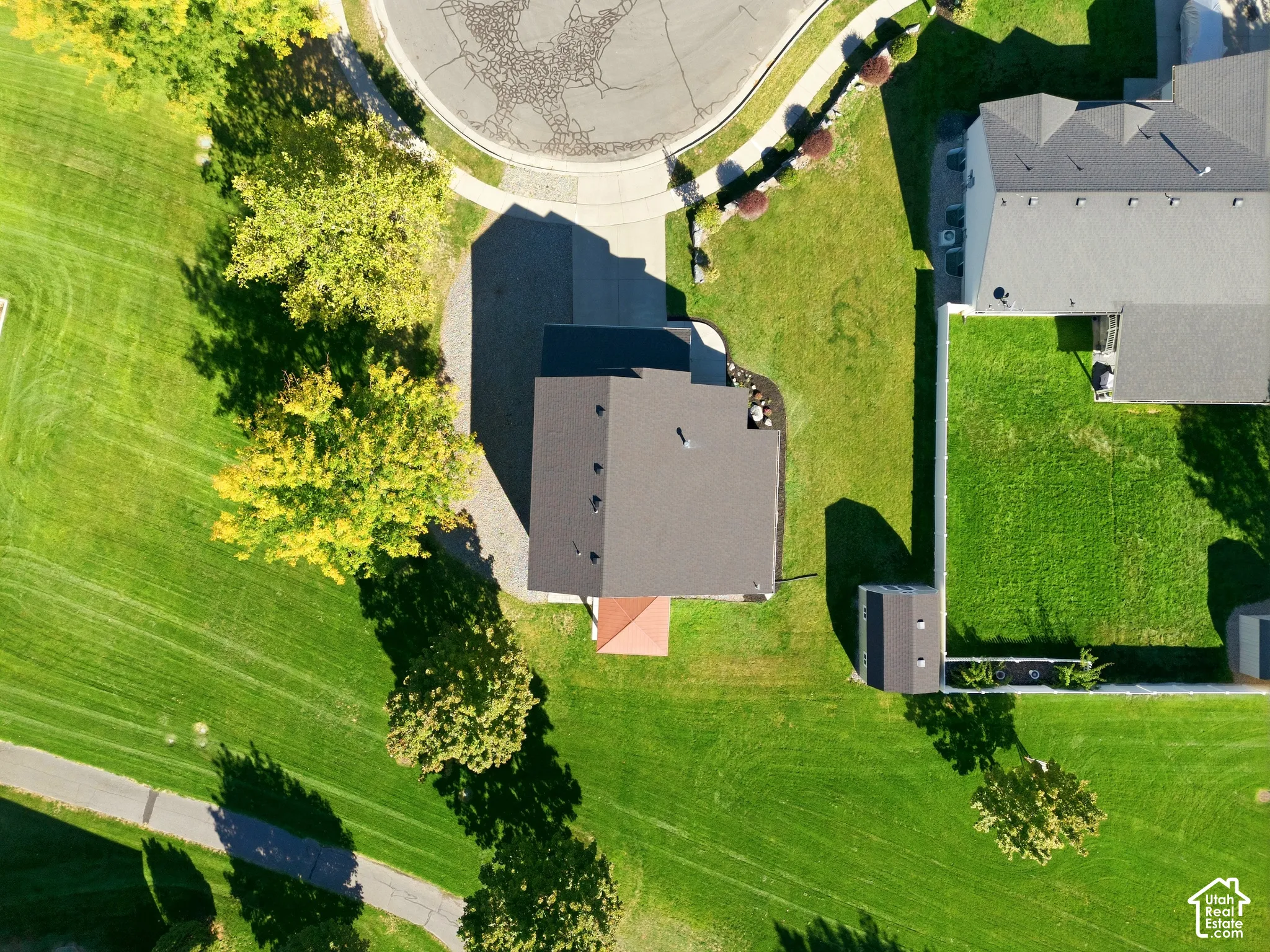 Spacious lot featuring a paved driveway, mature trees, and a detached shed