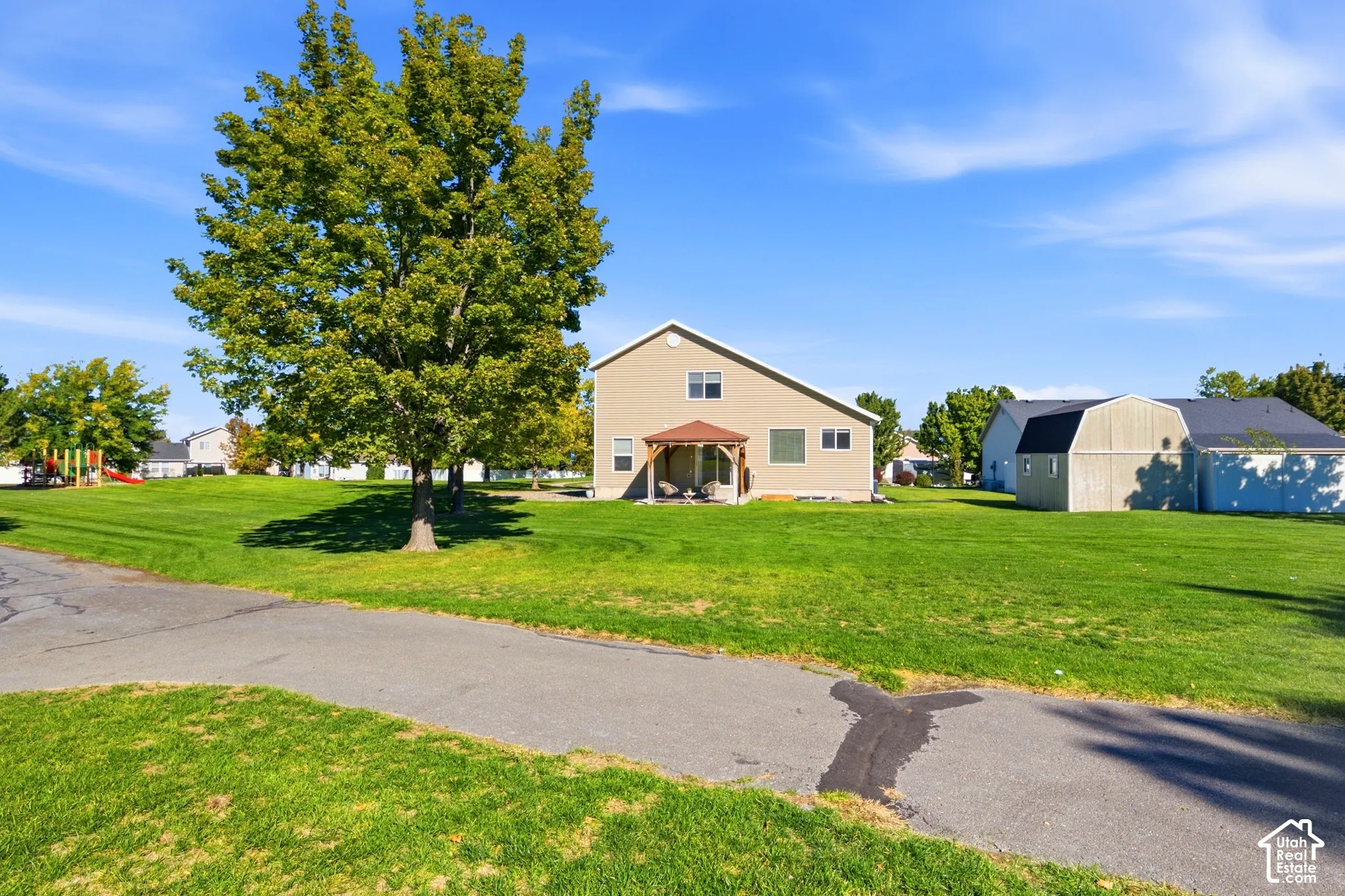 Expansive green lawn with mature trees and paved path