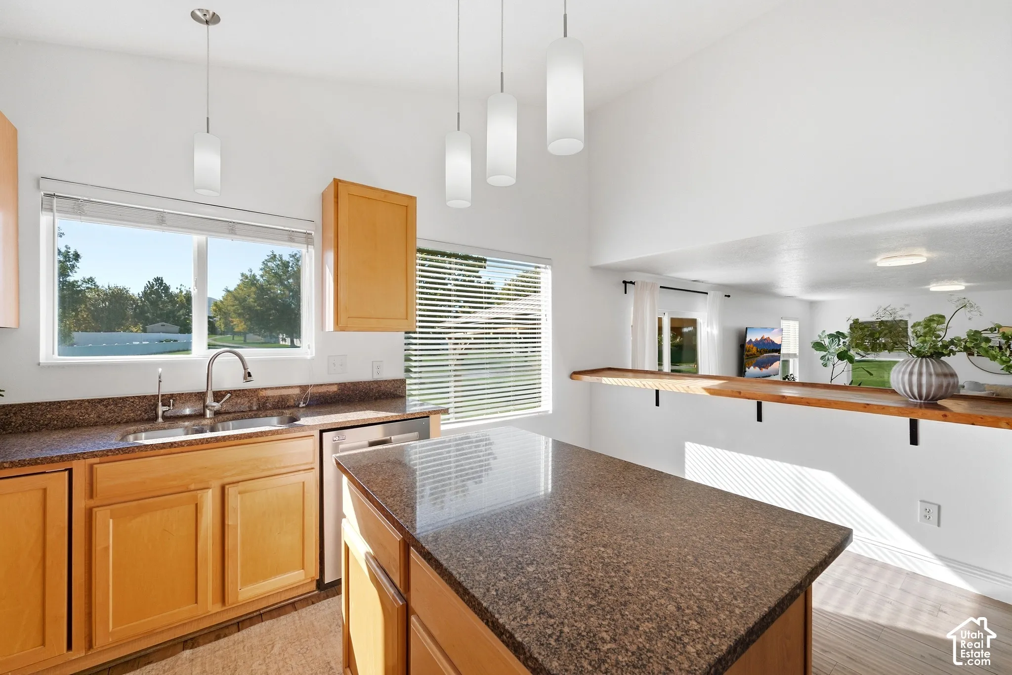 Kitchen featuring light wood cabinetry, granite-finish countertops, and a stainless steel sink with a gooseneck faucet