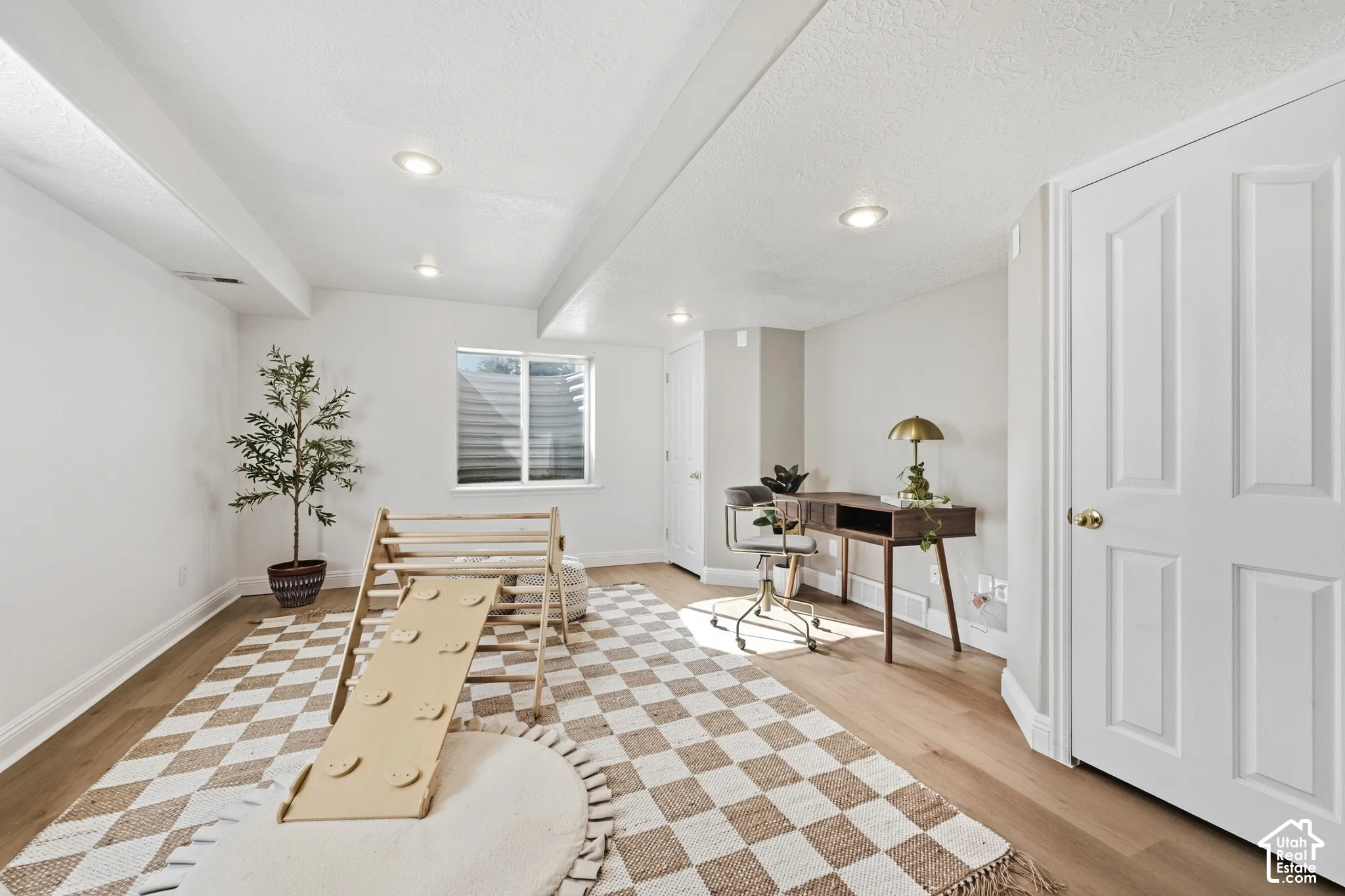 Recessed ceiling lighting, durable wood-finish flooring, white trim, a window with horizontal blinds, and a four-panel door with brass hardware