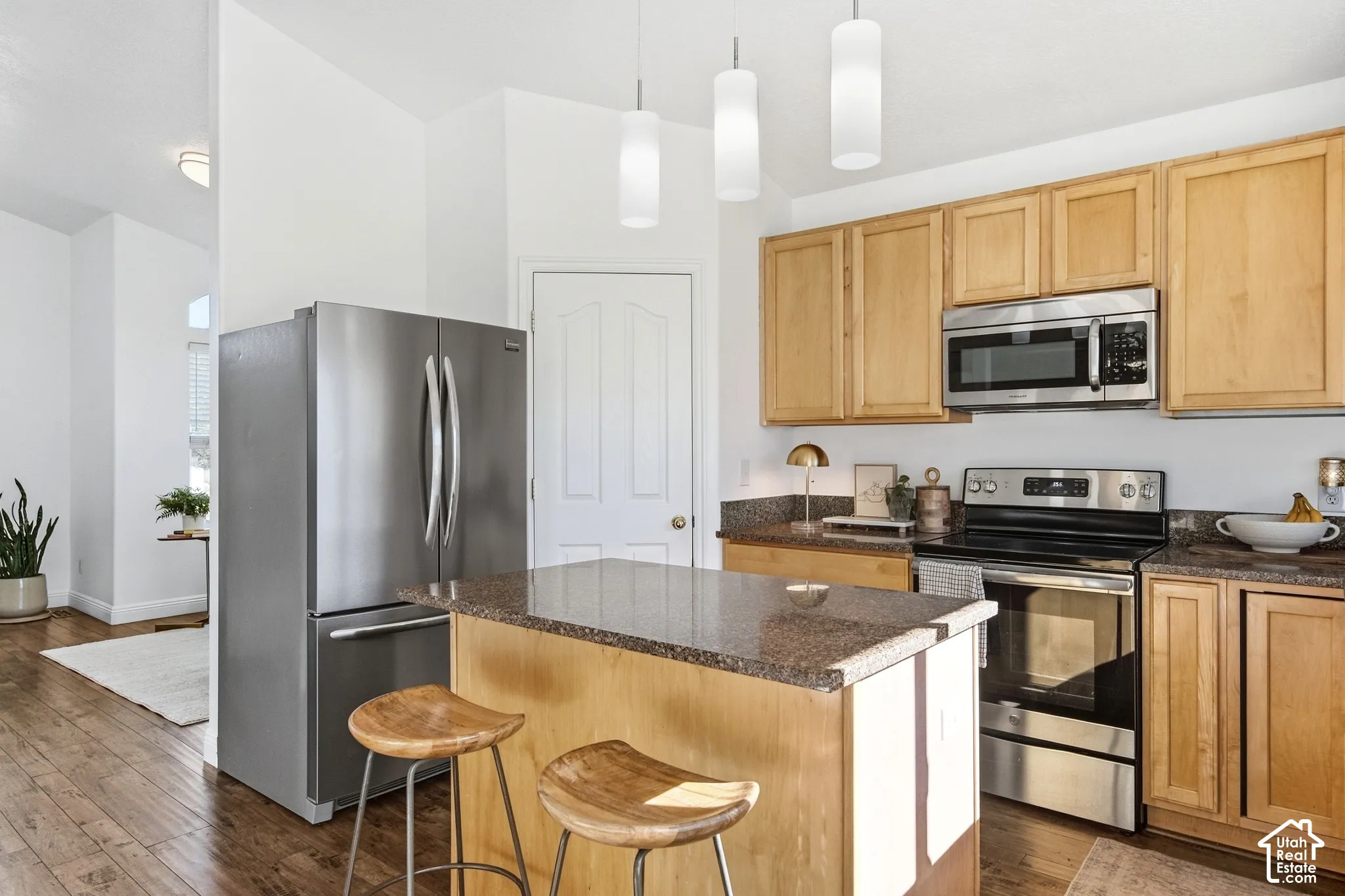 Kitchen featuring wood-finish flooring, an island with a countertop, stainless steel appliances, and wood cabinetry