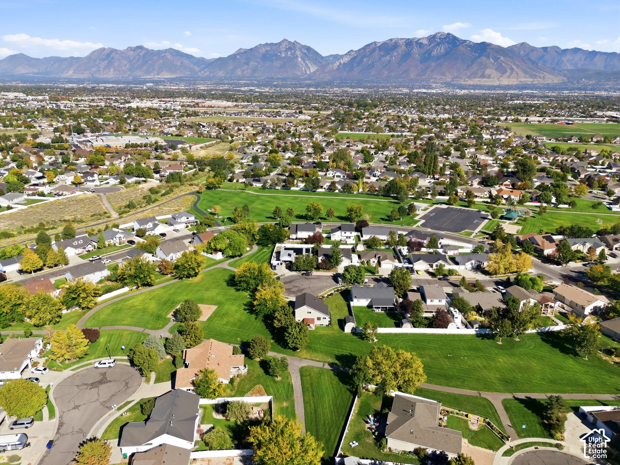 Mountain backdrop with extensive residential development, green spaces, and mature tree coverage