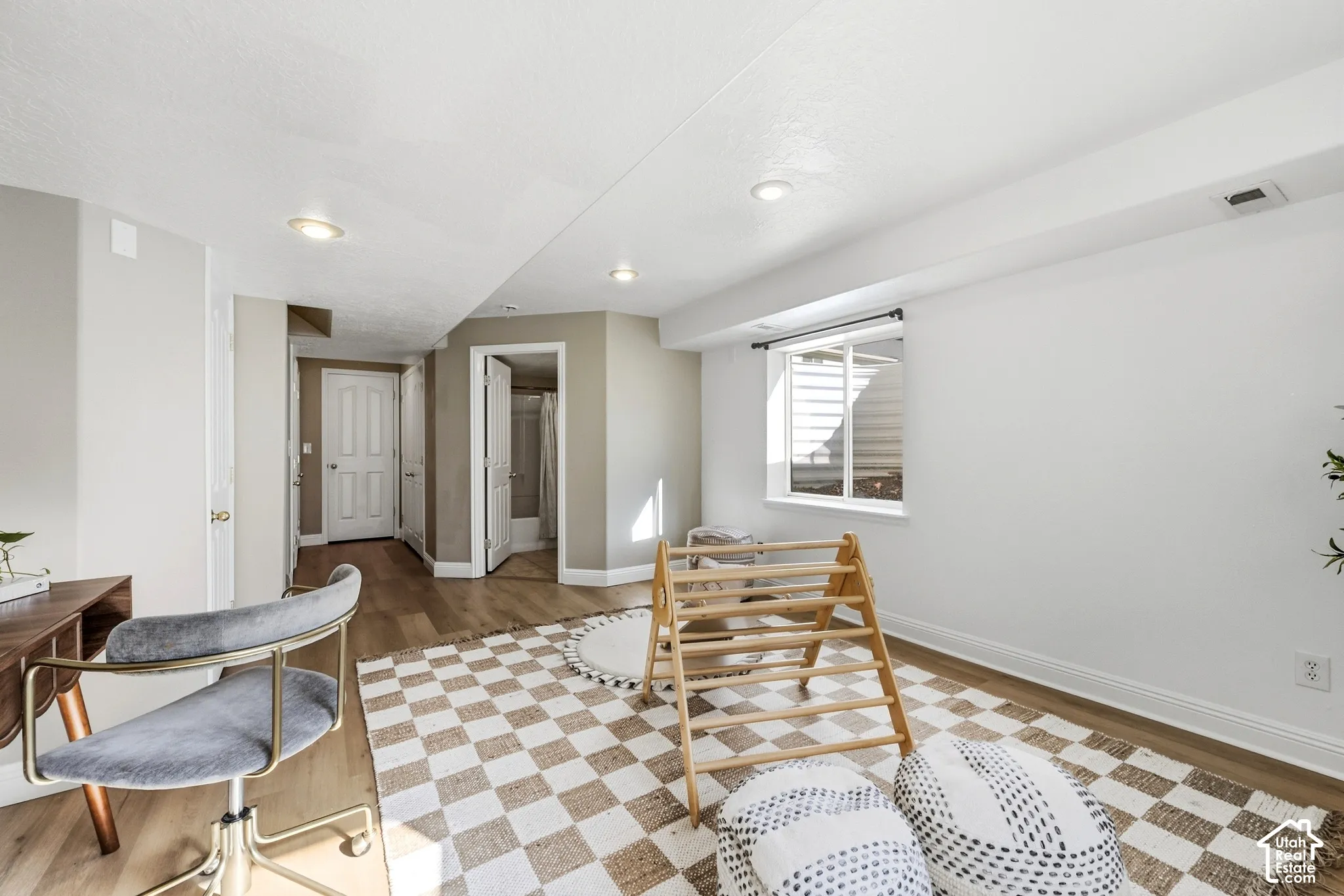 Recessed lighting, wood-finish flooring, white trim, and a window with a white frame