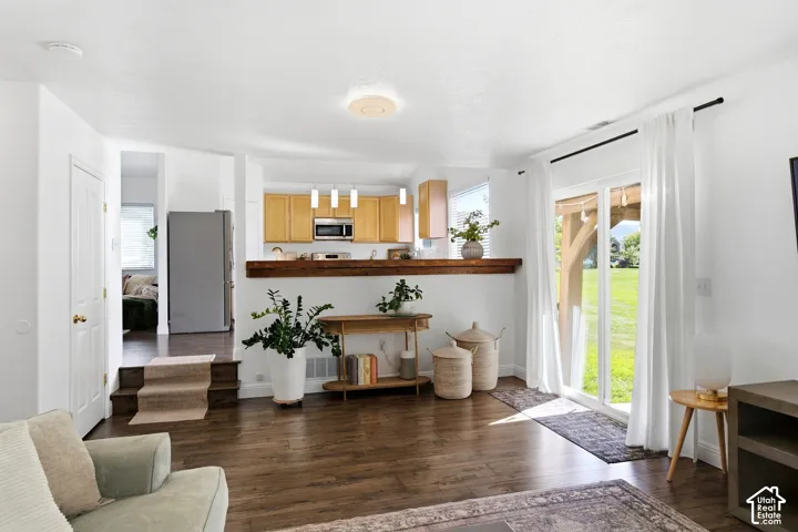 Wood-finish flooring throughout, with a kitchen featuring light wood cabinetry, stainless steel appliances, and a wood-finish breakfast bar